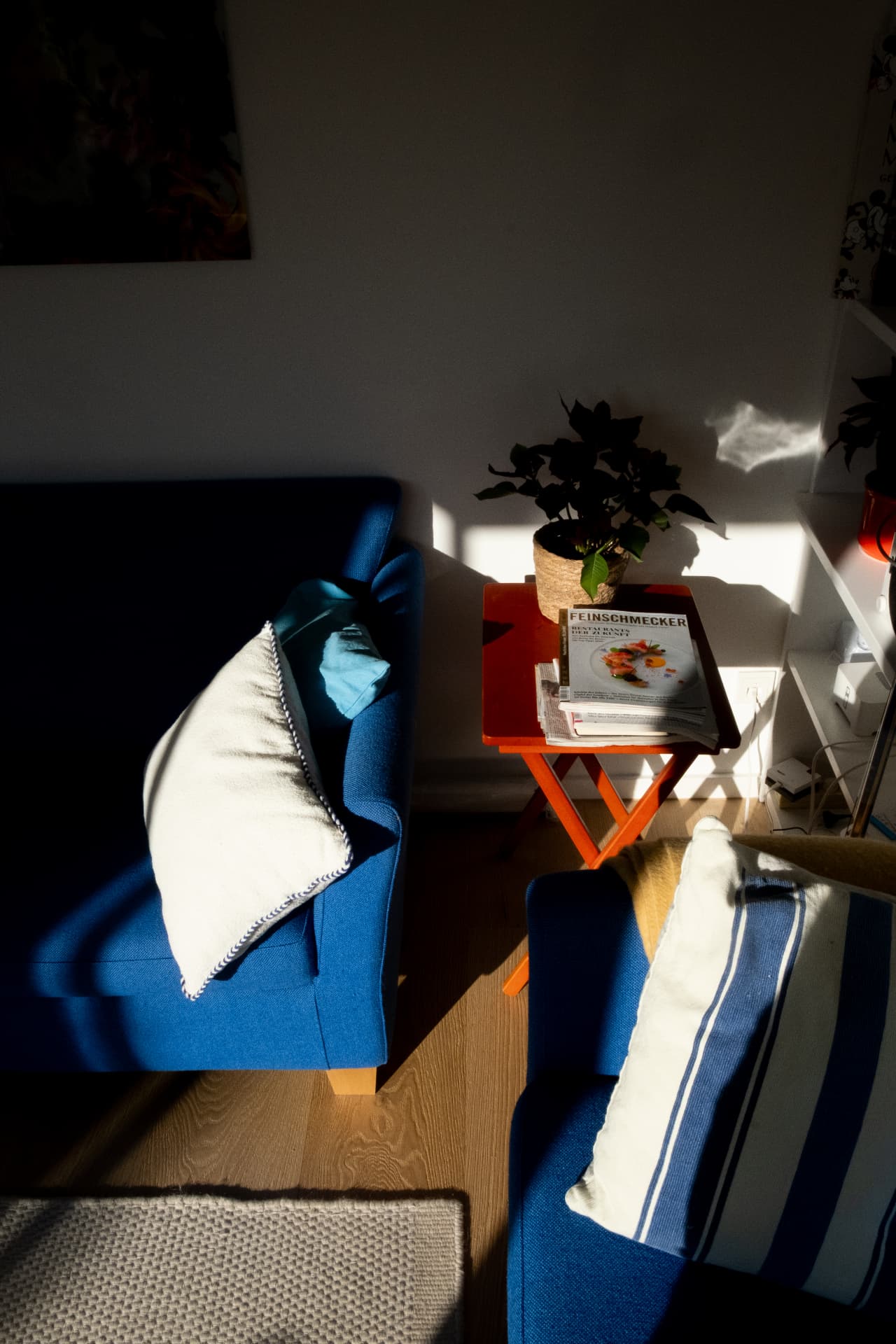 Low evening light falling across a blue sofa and small orange side table