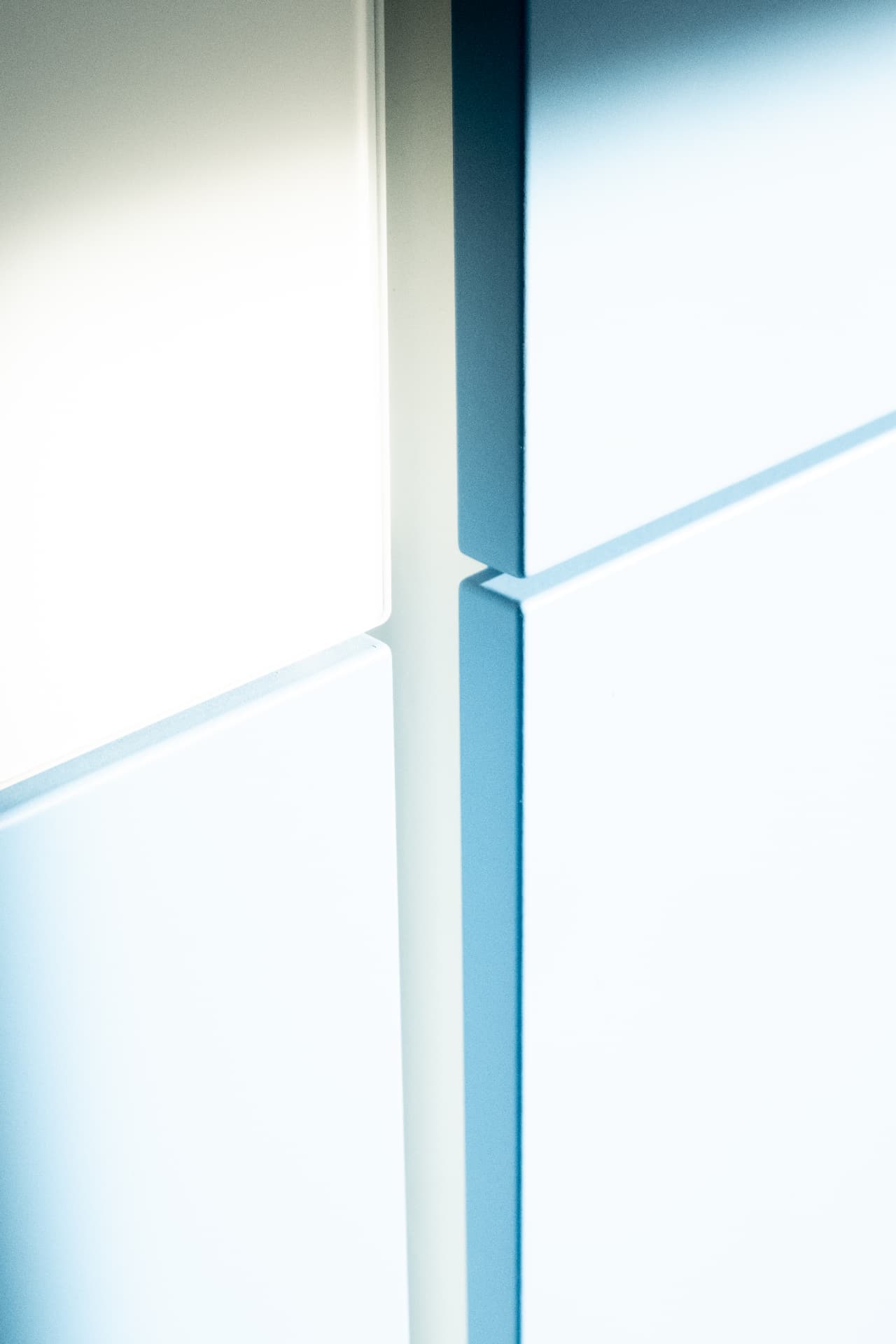 Close-up of a shadow-gap joint between white and blue cabinet fronts