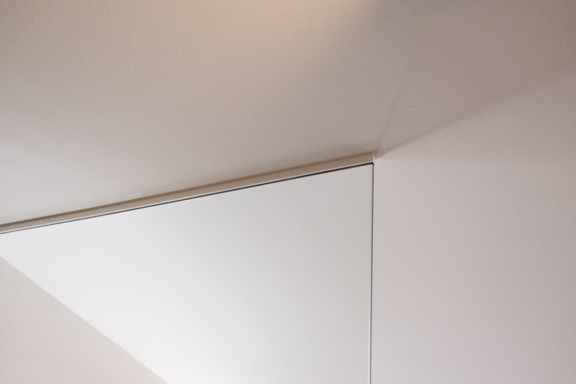 Shadow-gap joint where a white built-in element meets the ceiling