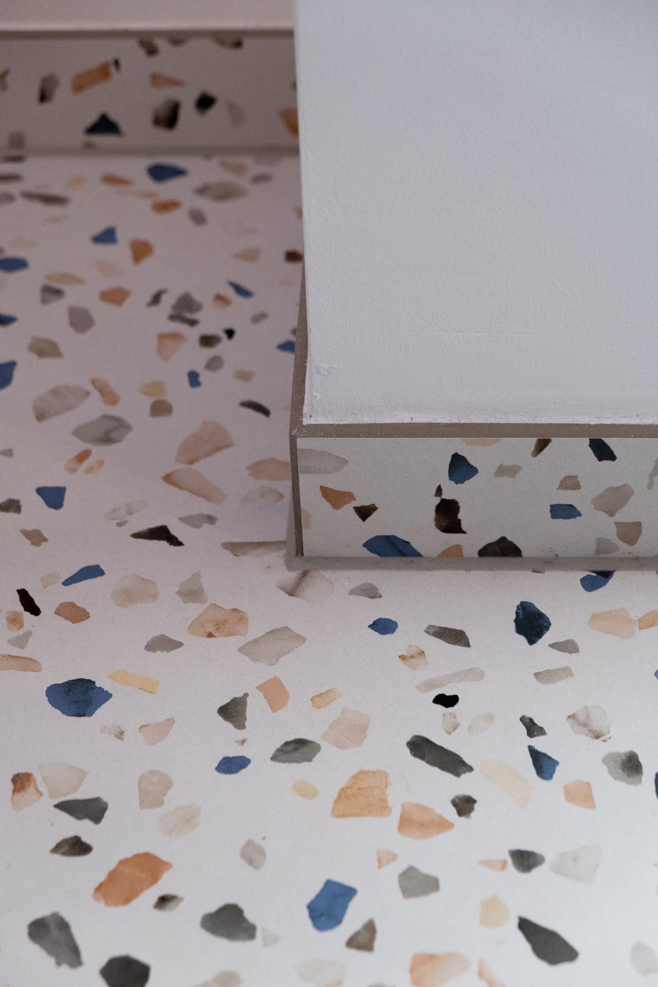 Terrazzo step detail with blue and ochre aggregate against white plaster