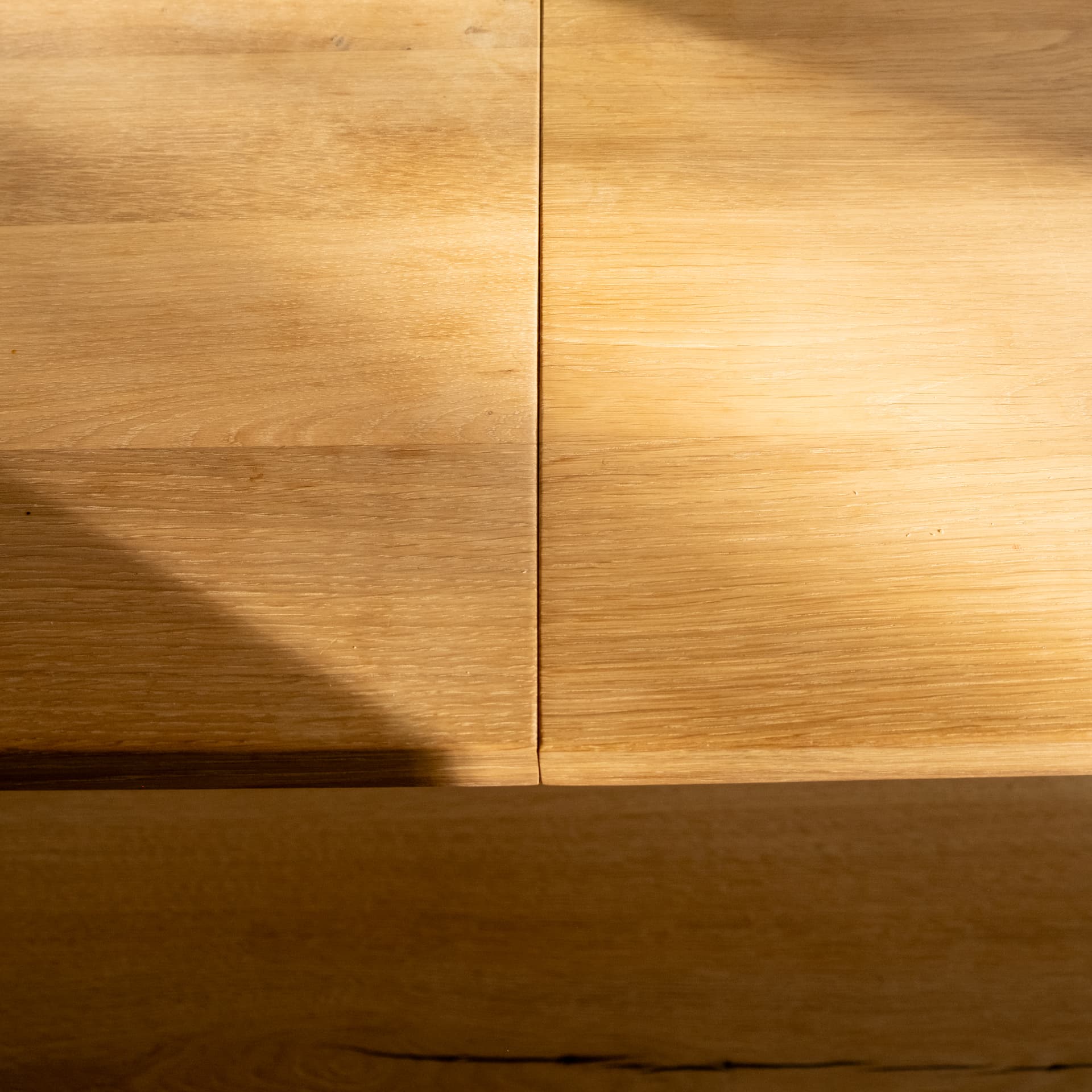 Sunlight crossing the joint of a solid oak tabletop